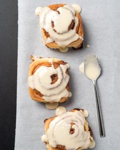 three cinnamon rolls with icing and a spoon