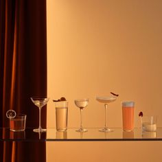 there are many glasses on the table with different drinks in them and one is empty