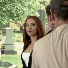 a woman with red hair standing next to a man