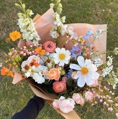 a bouquet of flowers sitting on top of a field next to a person's leg