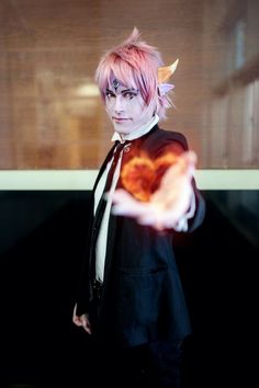 a man with pink hair and horns holding a heart shaped object in front of him