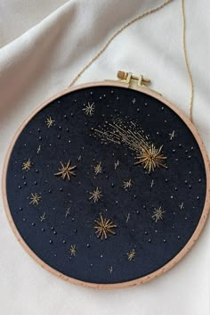 a cross stitch pattern with gold stars and sparkles in the sky on a white background