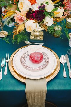 a table set with plates, silverware and flowers