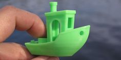 a hand holding a green plastic toy boat