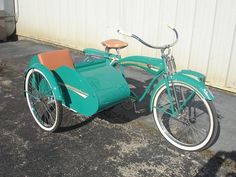 an old fashioned bicycle with sidecar parked in front of a building on the street