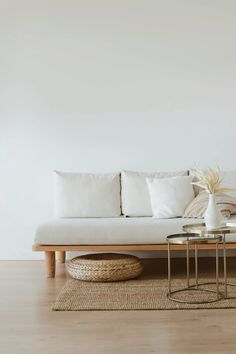 a white couch sitting on top of a wooden floor next to a table with two vases