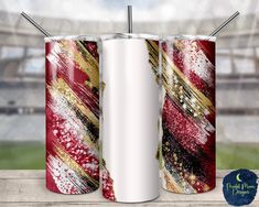 two red, white and gold cans with straws in them on a wooden table