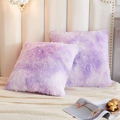 two purple pillows sitting on top of a bed