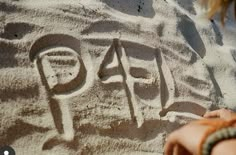 a person writing on the sand with their hand