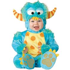 a baby in a blue and yellow monster costume sitting on the ground with his hands up