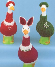 three knitted ducks wearing sweaters and hats