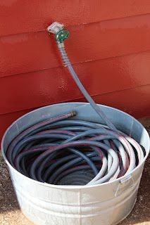 a bucket filled with water and hoses next to a red wall