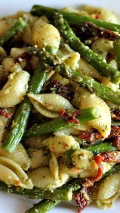 pasta with asparagus, sun dried tomatoes and parmesan cheese on a white plate