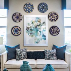 a living room filled with lots of blue and white decorations on the wall next to a couch