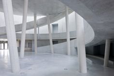 the interior of an empty building with columns and concrete flooring in front of it