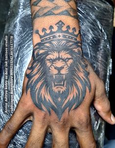 a man's hand with a lion tattoo on it and a crown in the middle