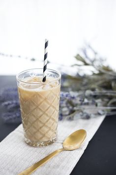 a glass filled with ice cream next to a spoon and flower on a tablecloth