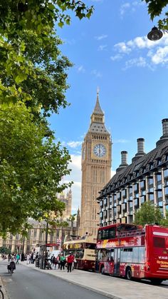 the big ben clock tower towering over the city of london as people walk down the street