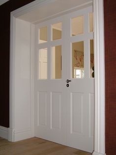 an empty room with two white doors and wood floors in front of the door is a brown wall