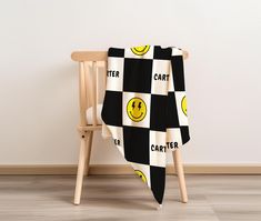 a black and white blanket sitting on top of a wooden chair next to a wall