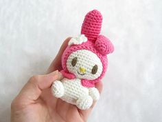 a hand holding a small crocheted hello kitty doll