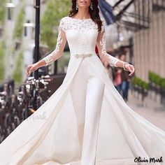 the woman is walking down the street wearing a white dress with long sleeves and lace detailing