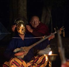 a man and woman sitting next to each other in the dark with candles around them