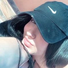 a woman with black hair wearing a nike hat