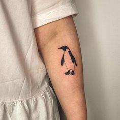 a small penguin tattoo on the left arm