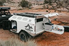 an off road camper parked in the desert with its door open and roof down