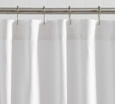 a white shower curtain hanging from a metal rod