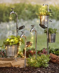 three metal planters with plants in them sitting on top of a wooden table next to some dirt