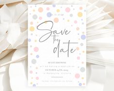 the save the date card is on top of some white paper with colorful polka dots