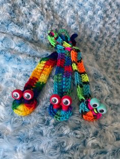 three crocheted toys are laying on top of a blue blanket, with eyes drawn on them