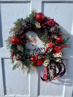 a christmas wreath hanging on the side of a white door with red and gold decorations