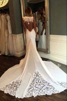 the back of a woman's wedding dress in front of a mirror