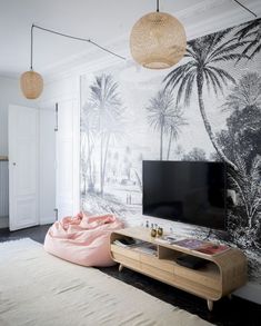 a living room with palm trees on the wall and a large tv in the corner