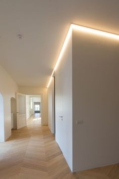 an empty room with white walls and wood floors is lit by led lighting on the wall