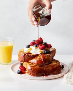 a person is pouring syrup on some french toast