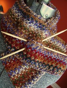 a multicolored knitted scarf with two knitting needles