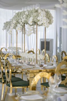 the tables are set with gold chairs and white flowers