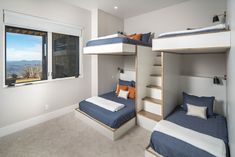 a bedroom with two bunk beds and a window overlooking the mountains in the back ground