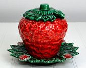 a red ceramic strawberry sitting on top of a green plate