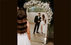 a bride and groom standing in front of a wedding photo