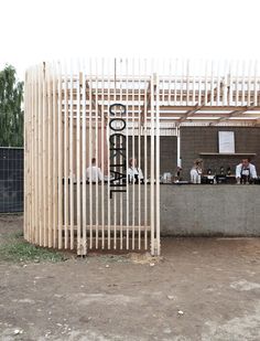 a group of people sitting at a table in front of a building with wooden slats on it