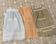 three skirts are lined up on a bed