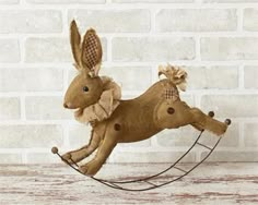 a brown stuffed animal is riding on a rocking horse with a bow around its neck