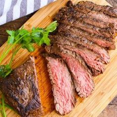 steak sliced up on a cutting board with parsley next to it, ready to be served