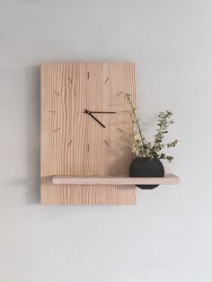 a wooden clock mounted to the side of a wall next to a vase with flowers