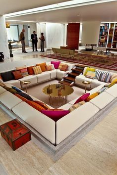 a living room filled with lots of couches and tables next to bookshelves